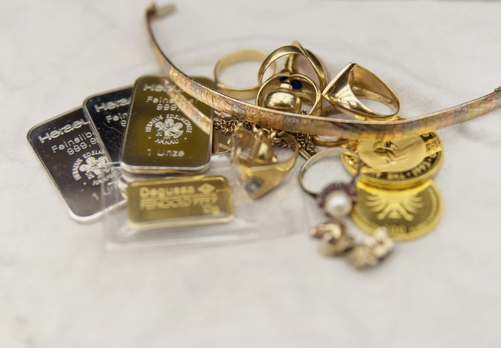 Altgold, Barren, Münzen und Schmuck auf hellem Tuch