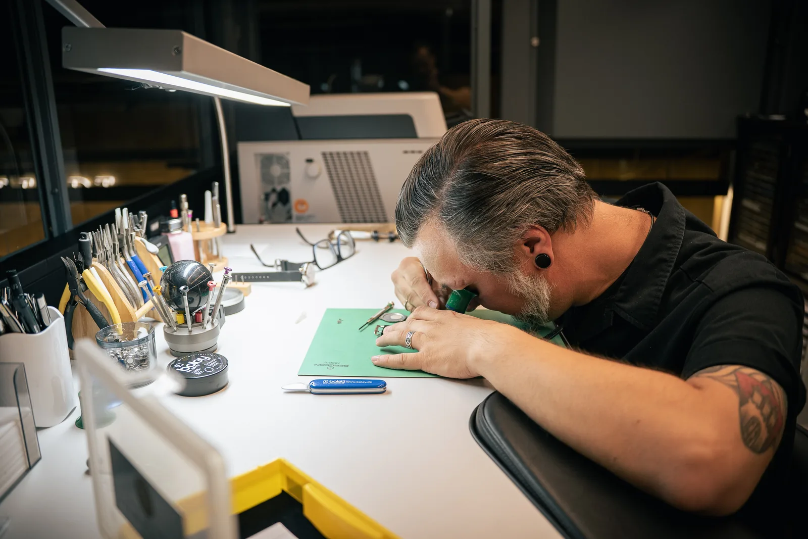 Uhrmacher mit Lupe bei der Arbeit an einem Uhrwerk
